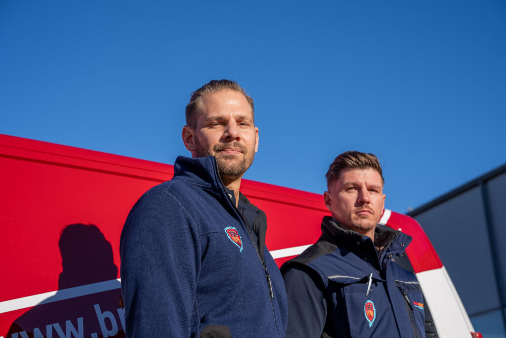 2 Brandschutzbeauftragte vor ihrem Dienstfahrzeug in Uniform