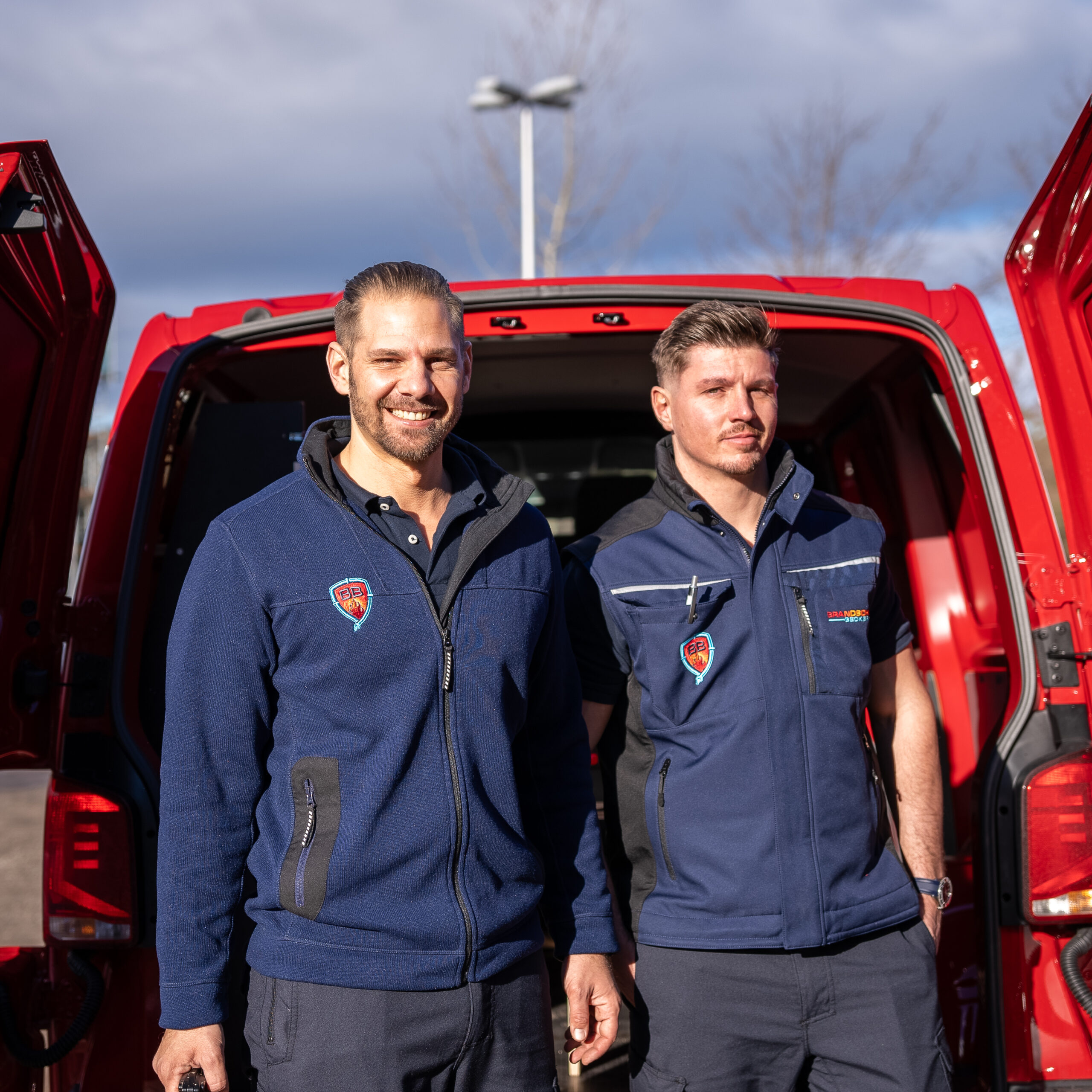 2 Brandschutzbeauftragte vor ihrem Dienstfahrzeug in Uniform